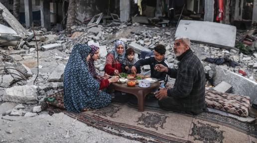 A family in Gaza eats a meal in the midst of the rubble of their home.